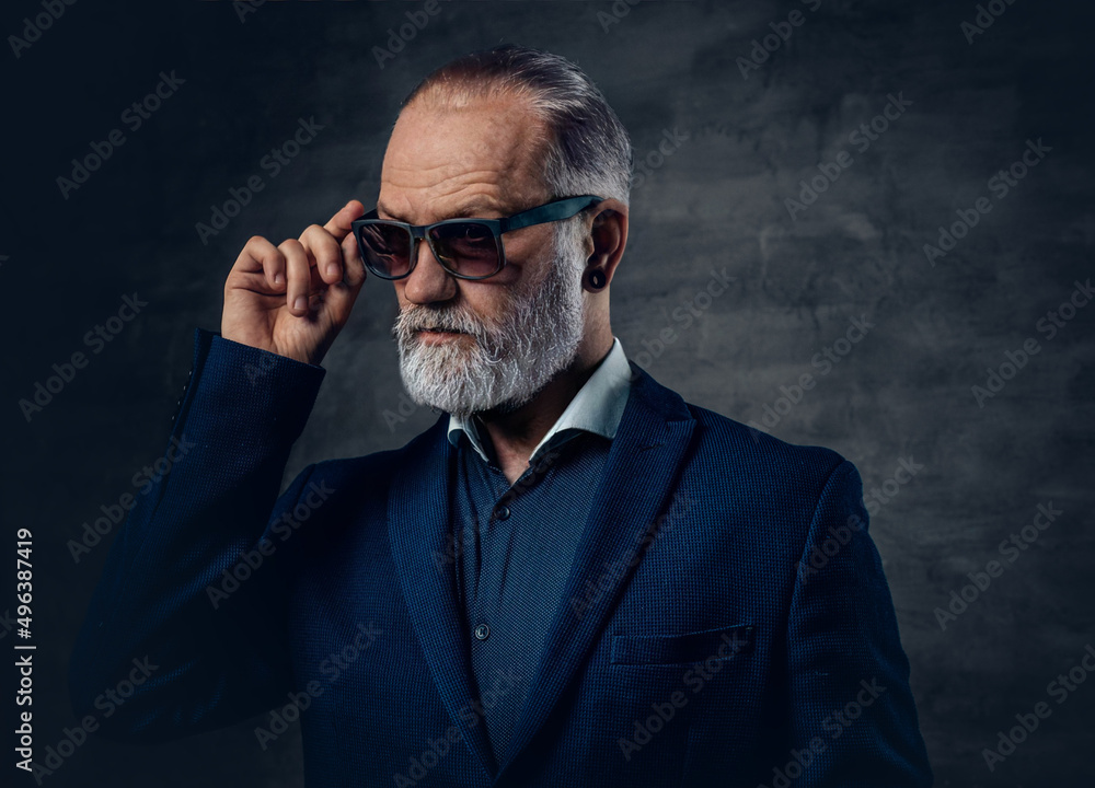 Fashionable old man with sunglasses dressed in dark blue jacket