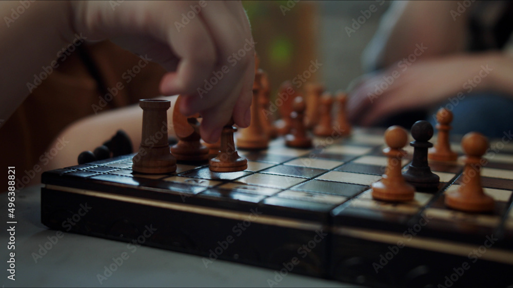 Mom watches her daughter play chess. The girl uncertainly makes a pawn move Mom watches her daughter play chess. The girl uncertainly makes a pawn move