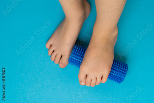 blue needle roller for massage and physiotherapy on a blue background with the image of a child's foot, the concept of prevention and treatment of hallux valgus