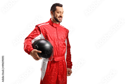 Smiling racer in a red suit holding a black helmet and looking to the side