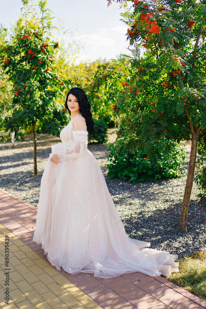 beautiful brunette bride in a wedding dress in a park with rowan trees. beautiful brunette bride in a wedding dress in a park with rowan trees.