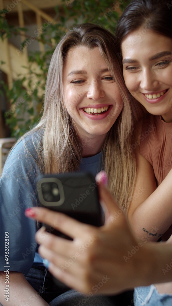 Two young lgbt ladies are talking with their friends on the video call, listening attentively and smiling, slow motion Two young lgbt ladies are talking with their friends on the video call, listening attentively and smiling, slow motion
