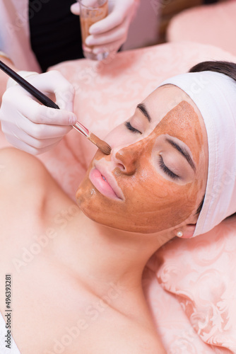 Girl with facial mask lying in beauty health spa center 