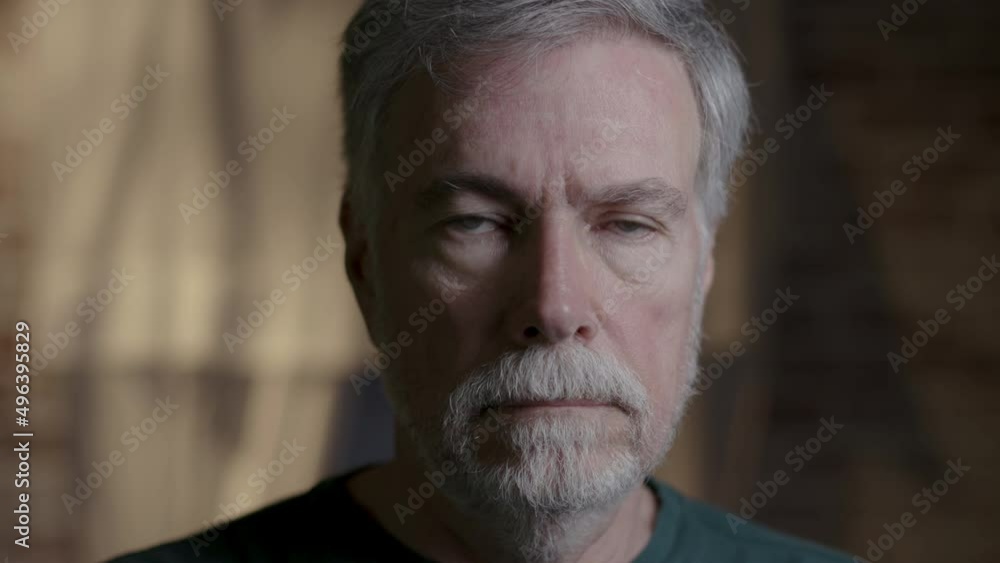 A solemn stern looking senior man walks forward then stops and stares into the camera. A solemn stern looking senior man walks forward then stops and stares into the camera.