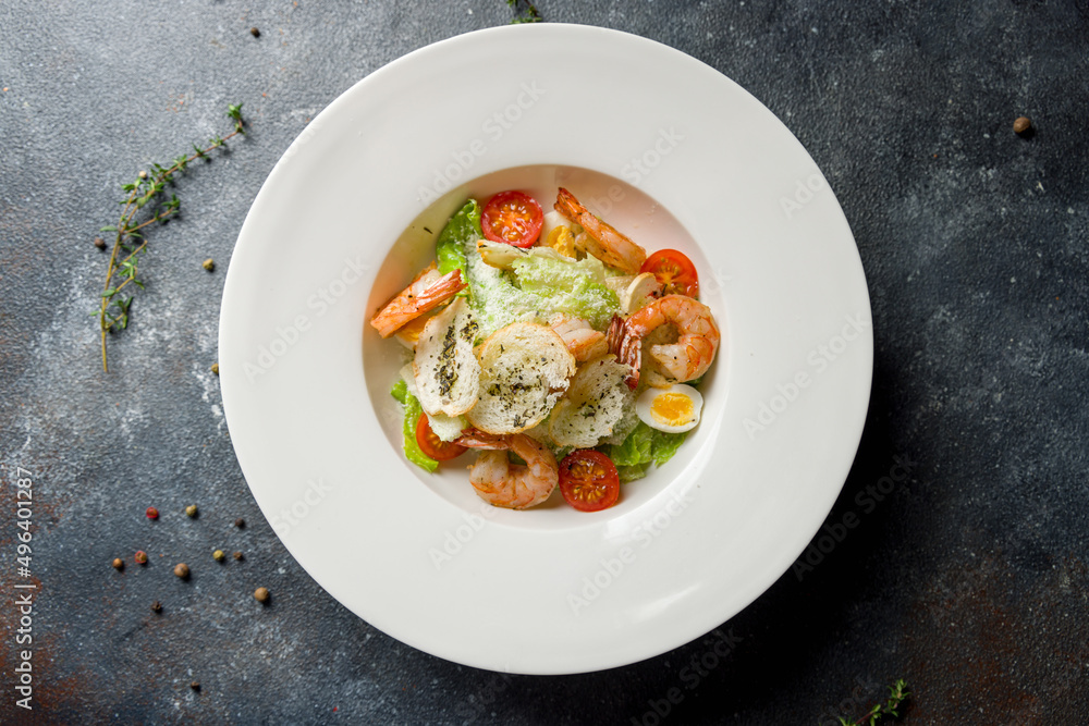 salad caesar with shrimps on white plate on concrete table top view salad caesar with shrimps on white plate on concrete table top view