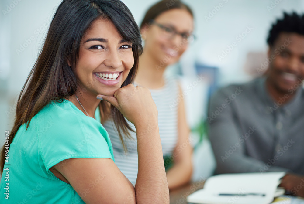 More than coworkers, theyre my friends. Portrait of an attractive young woman sitting at a table with colleagues in the background. More than coworkers, theyre my friends. Portrait of an attractive young woman sitting at a table with colleagues in the background.