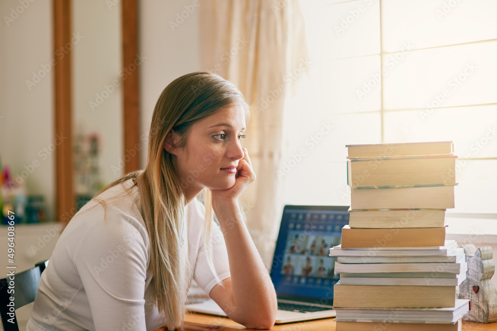 Thats an overwhelming amount of information. Shot of a young woman looking overwhelmed by the pile of books on her desk. Thats an overwhelming amount of information. Shot of a young woman looking overwhelmed by the pile of books on her desk.