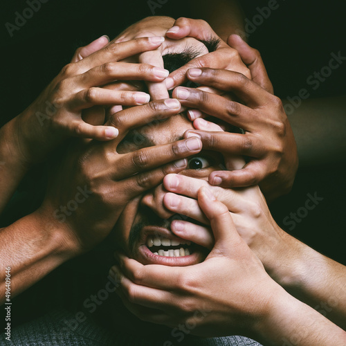 How do you wake from a nightmare when you arent asleep. Shot of hands grabbing a young mans face against a dark background. photo