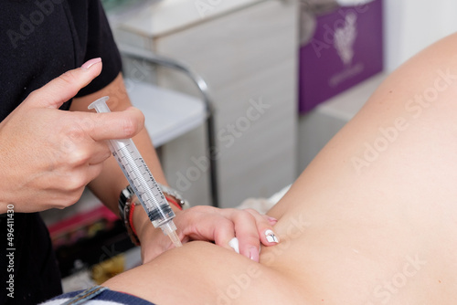 Fat reduction in the abdomen. Treatment that prevents abdominal fat. The specialist applies a treatment to a young man with a fair complexion who is in a clinic specializing in skin rejuvenation.