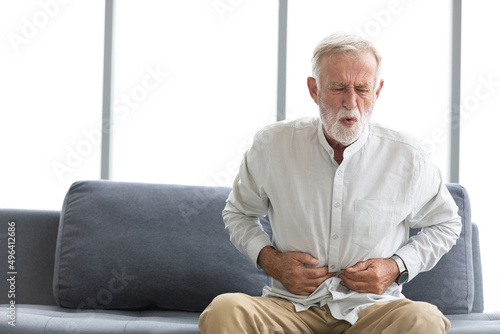 senior man have a stomachache  and holding stomach on sofa photo