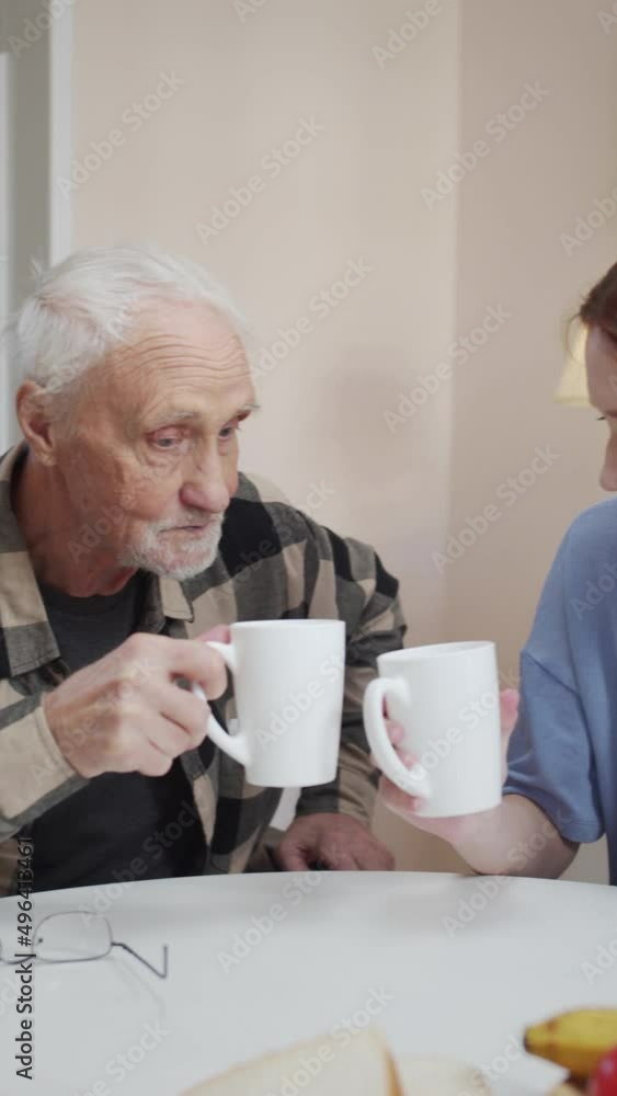 Family get togethers. Woman drinking tea with her elderly father and clinking glasses Family get togethers. Woman drinking tea with her elderly father and clinking glasses