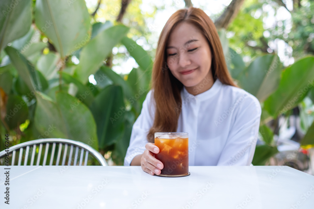 Portrait image a young asian woman holding and drinking iced coffee in the outdoors Portrait image a young asian woman holding and drinking iced coffee in the outdoors