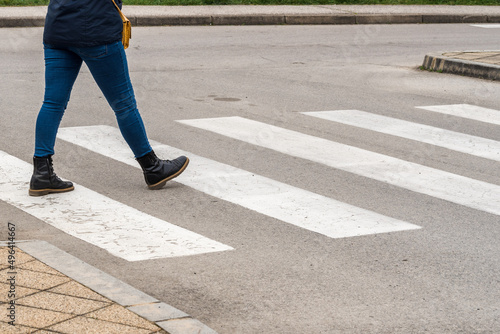 Pedestrians crossing. Woman legs in boots crossing the zebra crossing 