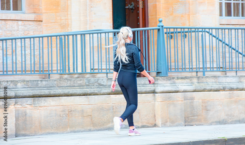 A beautiful blond young girl walks on the road and listens to music - Oxford, UK