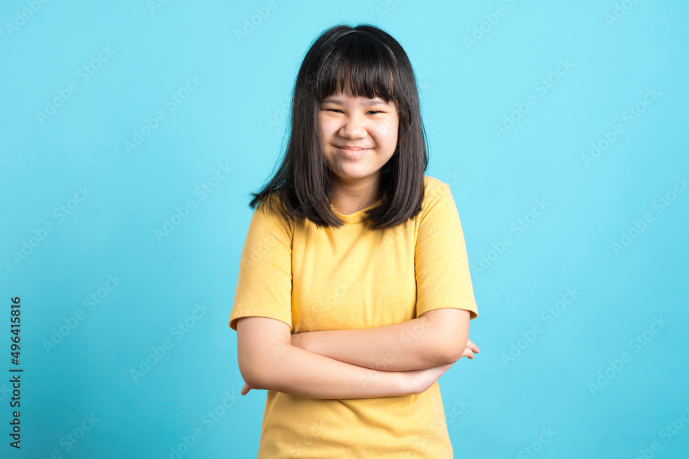 Cute Asian girl in yellow shirt laugh and standing on blue background. Cute Asian girl in yellow shirt laugh and standing on blue background.