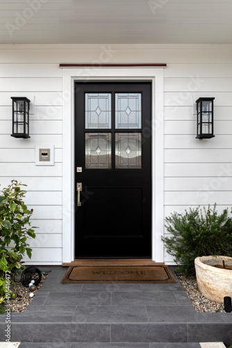 Ornate windows inserts on a black front door of a house.