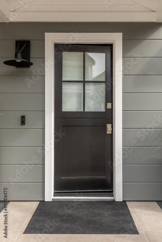 Black front door with window panes showing a reflection.