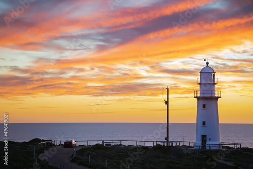 Landscape with white lighthouse at sunset at the sea coast