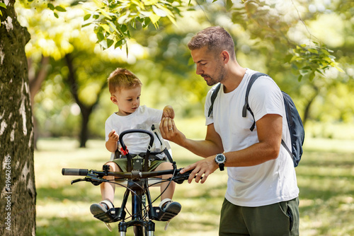 A father giving son a snacks while taking a break from cycling in nature.