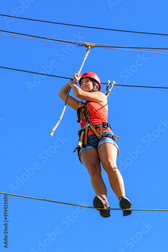Junge Frau balanciert auf einem wackeligen Hochseil im Seilpark