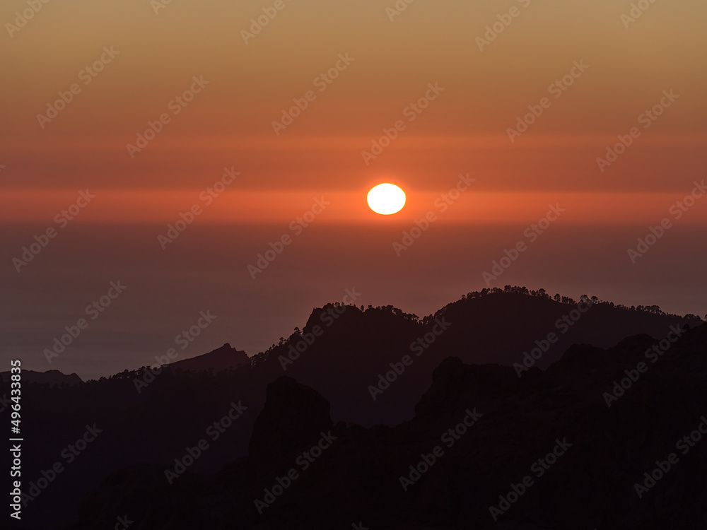 Majestic sunset above the Atlantic Ocean with red sun in the colorful dramatic sky viewed from Roque Nublo, Gran Canaria, Canary Islands, Spain.