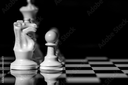 Close up of Chess pieces on a reflective mirror board surface with black background