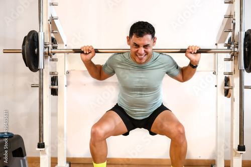 A caucasian man in the gym lifting weights with a lot of effort, healthy and healthy life doing sports