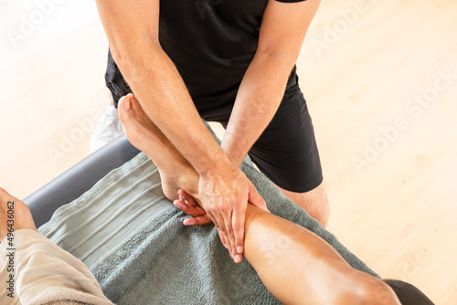 Detail of the therapeutic ankle massage and sports recovery osteopathy. Sportsman receiving a massage by a physiotherapist on a stretcher