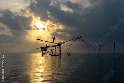 A fisherman is fishing in the lake at sunrise.