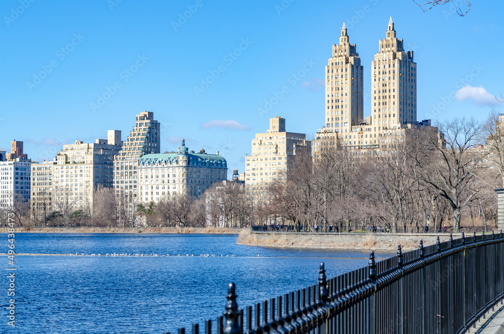 El Dorado Building with Jacqueline Kennedy Onassis Reservoir Lake and fence in forefront during daylight with clear sky, Central Park New York City, horizontal