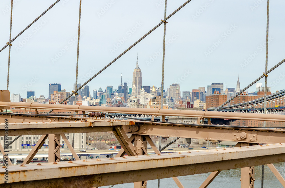 Manhattan Bridge with brown steel construction of Brooklyn Bridge in forefront, New York City, Empire State Building in the Background, horizontal