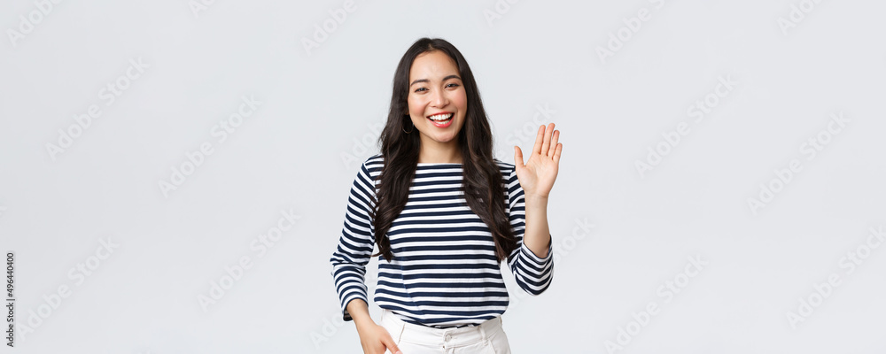 Lifestyle, people emotions and casual concept. Friendly cheerful asian woman smiling, saying hi and waving hand to greet person, make hello gesture, welcome someone - obrazy, fototapety, plakaty 