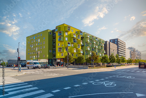 A modern residential building Ørestad plejecenter in bright light green color with windows and balconies in the form of cubes. Copenhagen, Denmark