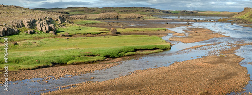 Panoramic view of a small river meandering through a green meadow. Iceland.