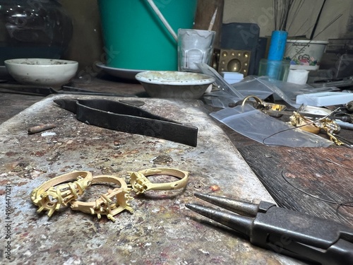 Gold rings setting with goldsmith tools on old cement plate. Vintage jewelers working wood table.