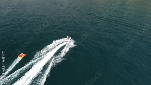 Wallpaper Mural Happy people are going to swim on an air mattress behind a jet ski. Tourists ride the inflatable watercraft boat. Sea attraction. Jet ski skating people on a large Inflatable raft. Aerial copter view. Torontodigital.ca