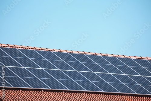 Solar photovoltaic panels on a house roof for renewable energy with blue sky