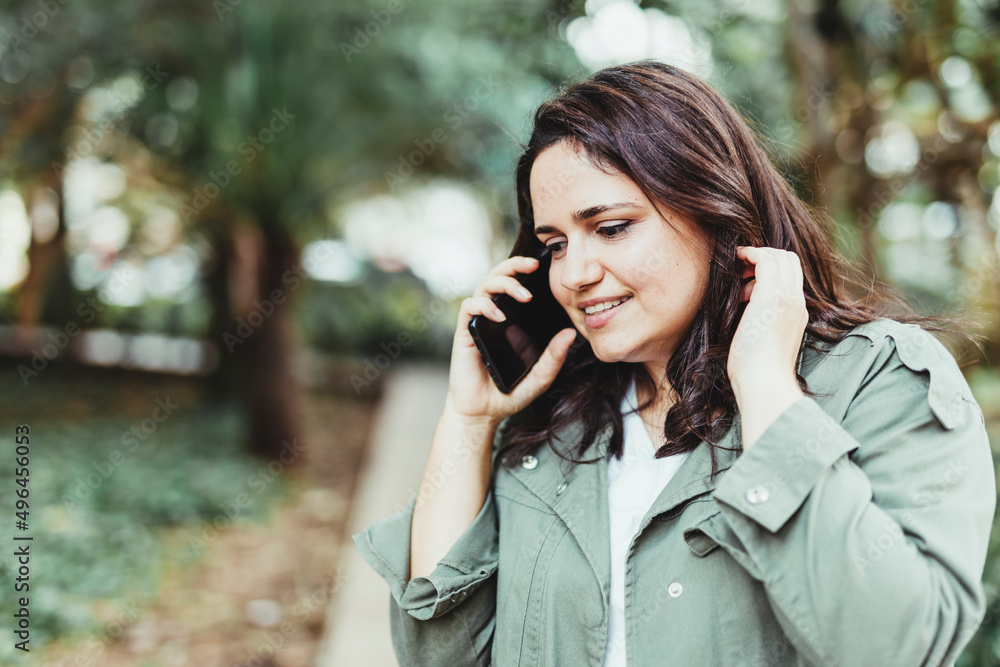 Selective focus of portrait of a smiling woman talking on the phone in the park Selective focus of portrait of a smiling woman talking on the phone in the park