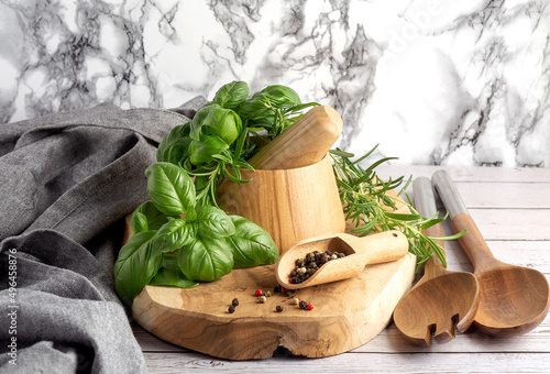 Herbs and Spices, Mortar and Pestle, wooden board, rosemary and basil, grey apron and wooden spoon