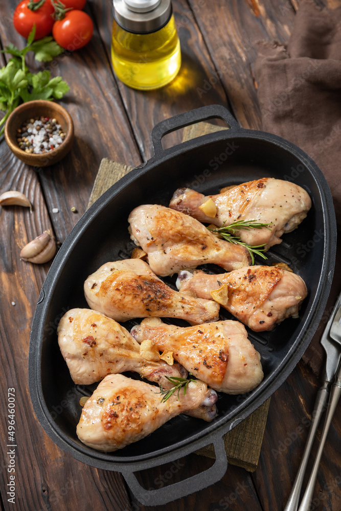 Baked grilled chicken legs with rosemary on a wooden table. Baked grilled chicken legs with rosemary on a wooden table.