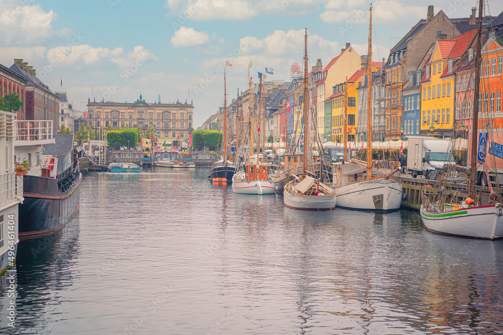 Nyhavn canal with many boats and yachts standing near colorful houses and Kongens Nytorv public square in Copenhagen, Denmark