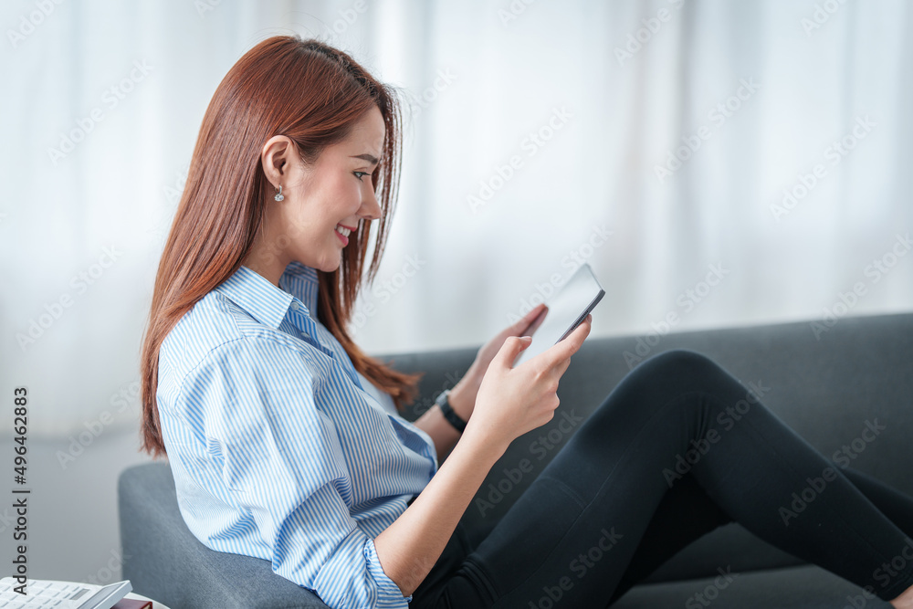 Woman enjoy with content streaming movies or social media application on digital tablet sitting on sofa at home. Woman enjoy with content streaming movies or social media application on digital tablet sitting on sofa at home.