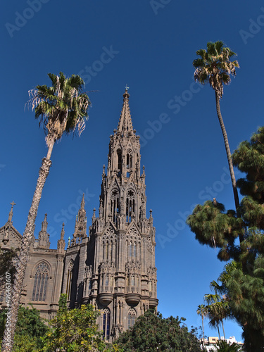 Low angle view of the steeple of famous Church of San Juan Bautista in the old center of town Arucas, Gran Canaria, Canary Islands, Spain with palms.
