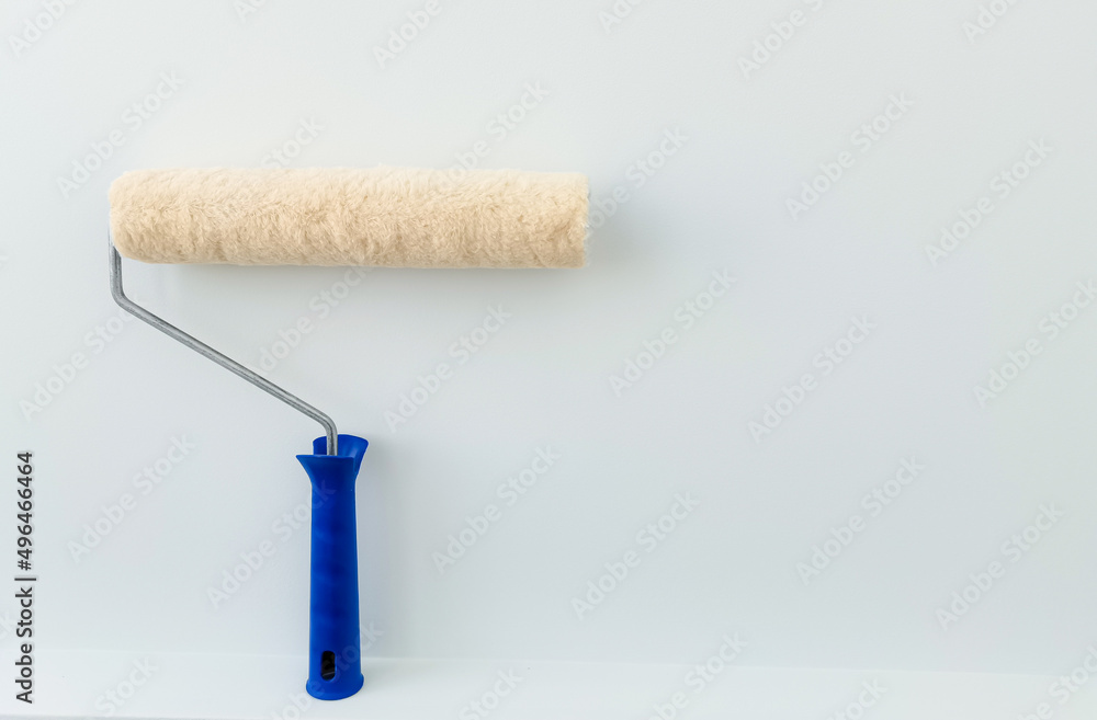 Obraz premium girl paints the wall with white paint. female hand with wall paint roller close up with copy space