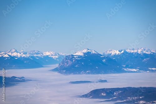 Panoramic view from Hochobir on snow capped mountain peaks of Karawanks in Carinthia, Austria. Julian Alps. Winter wonderland in the Austrian Alps, Europe. Valley covered with clouds. High Tauern Alps © Chris