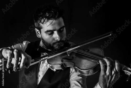 Violinista apuesto y vestido formalmente tocando música clasica photo