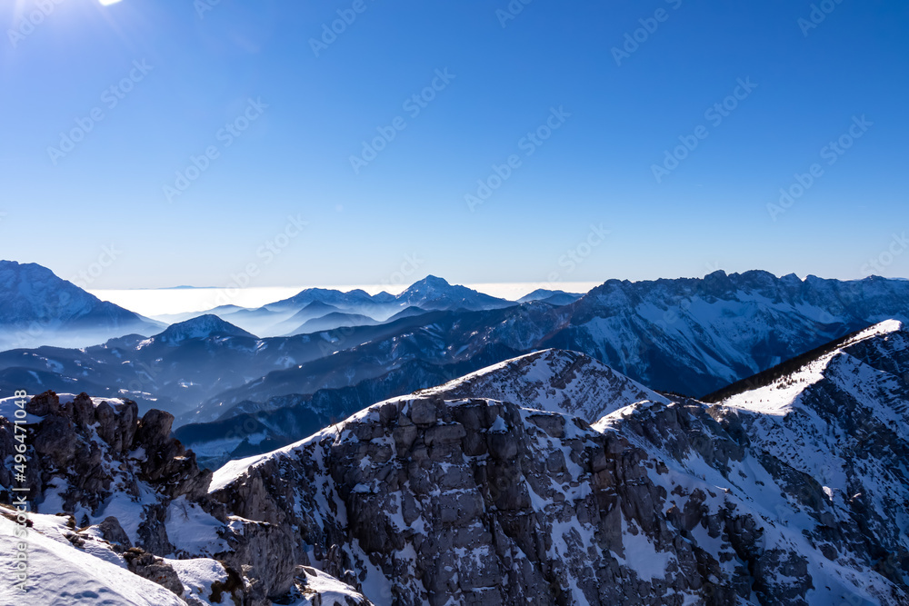 Fototapeta premium Scenic view from the summit of mount Hochobir on snow capped mountain peaks in the Karawanks in Carinthia, Austria. Winter wonderland on sunny day in Austrian Alps, Europe. Ski tour, snow shoe hiking.