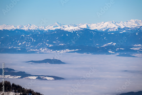 Panoramic view from Hochobir on snow capped mountain peaks of Karawanks in Carinthia  Austria. Julian Alps. Winter wonderland in the Austrian Alps  Europe. Valley covered with clouds. High Tauern Alps