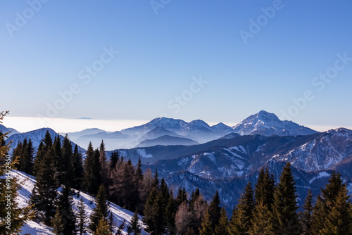 Panoramic view on snow capped mountain peaks of Karawanks in Carinthia, Austria. Julian Alps. Winter wonderland in the Austrian Alps, Europe. Ski tour, snow shoe hiking. Hochobir. Blue misty hills. © Chris