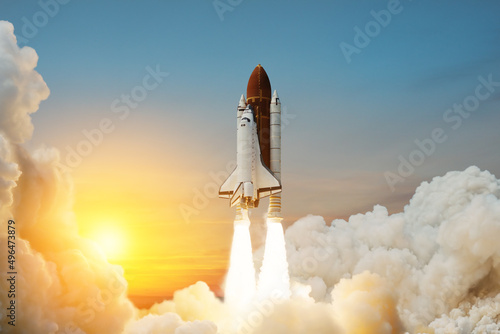 Fototapeta Naklejka Na Ścianę i Meble -  Spaceship lift off. Space shuttle with smoke and blast takes off into space on a background of sunset. Successful start of a space mission. Travel to Mars. Elements of this image furnished by NASA.
